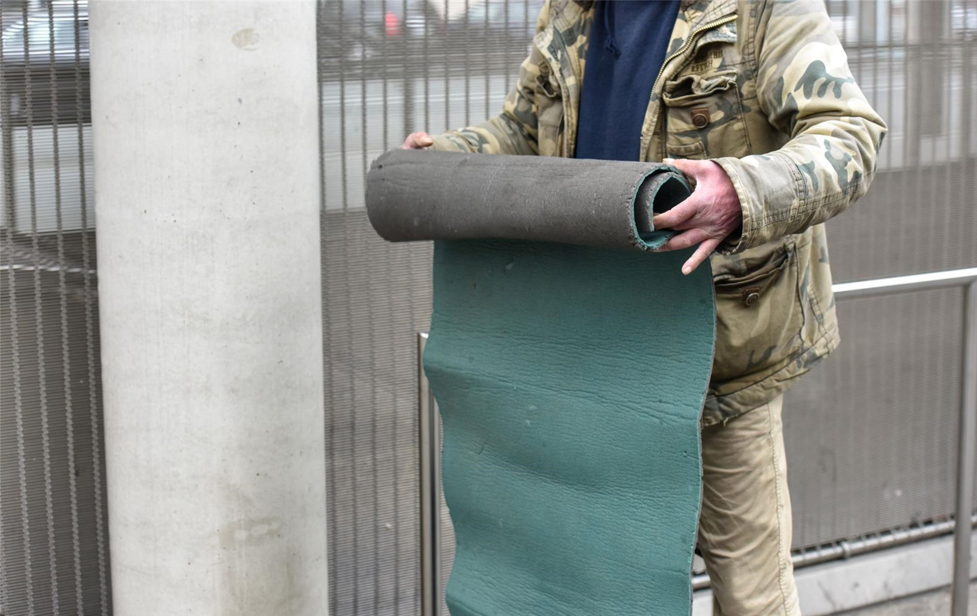 ein Obdachloser rollt seine Sitzmatte aus