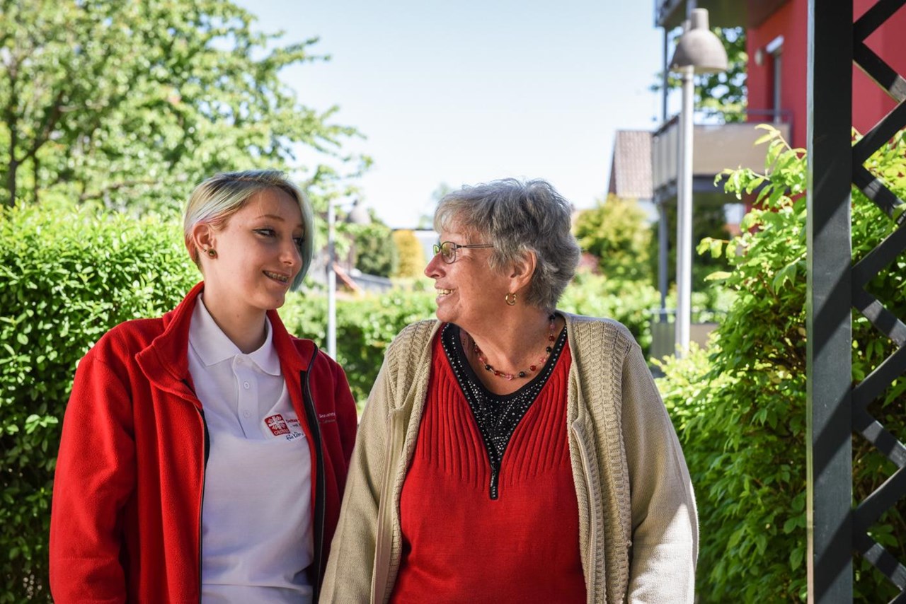 ältere Dame und Begleiterin schauen sich lächelnd an